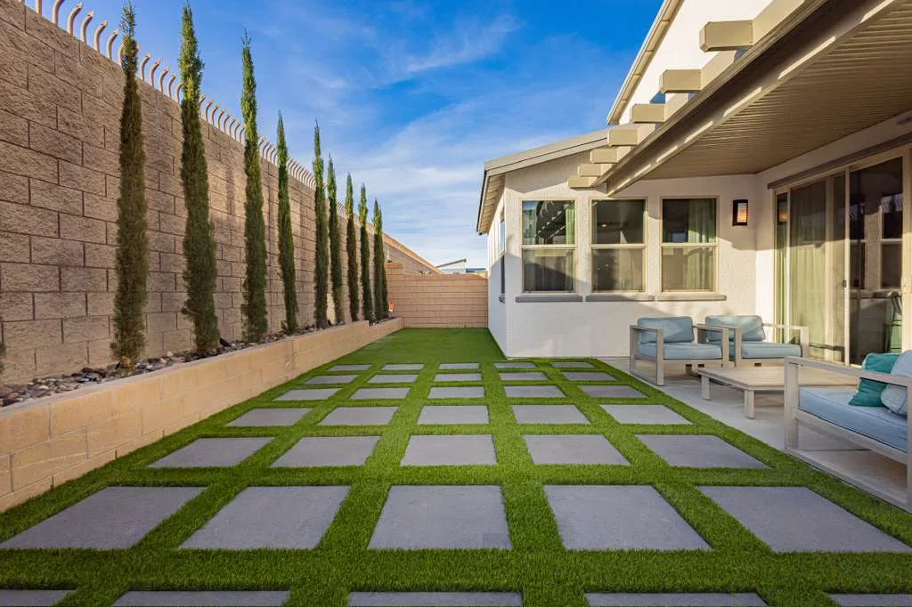 Peaceful backyard garden at Harmony House with stepping stones and cypress trees